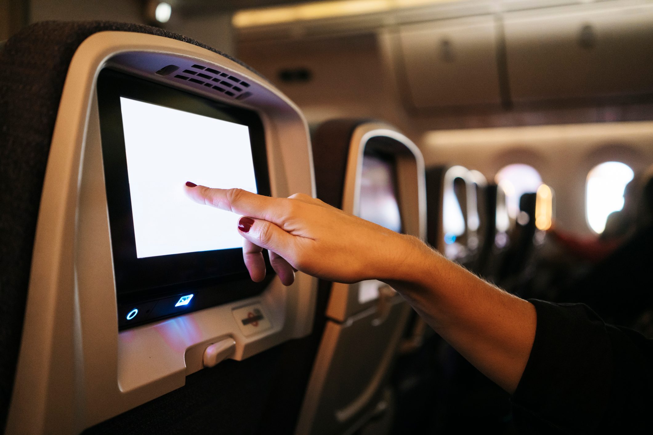 woman's hands using the touch screen of an airplane