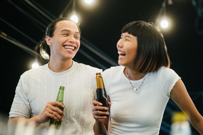 Young asian couple toasting with beer at rooftop party