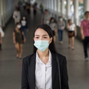 Asian woman with protective face mask in the urban bridge in city against crowd of people