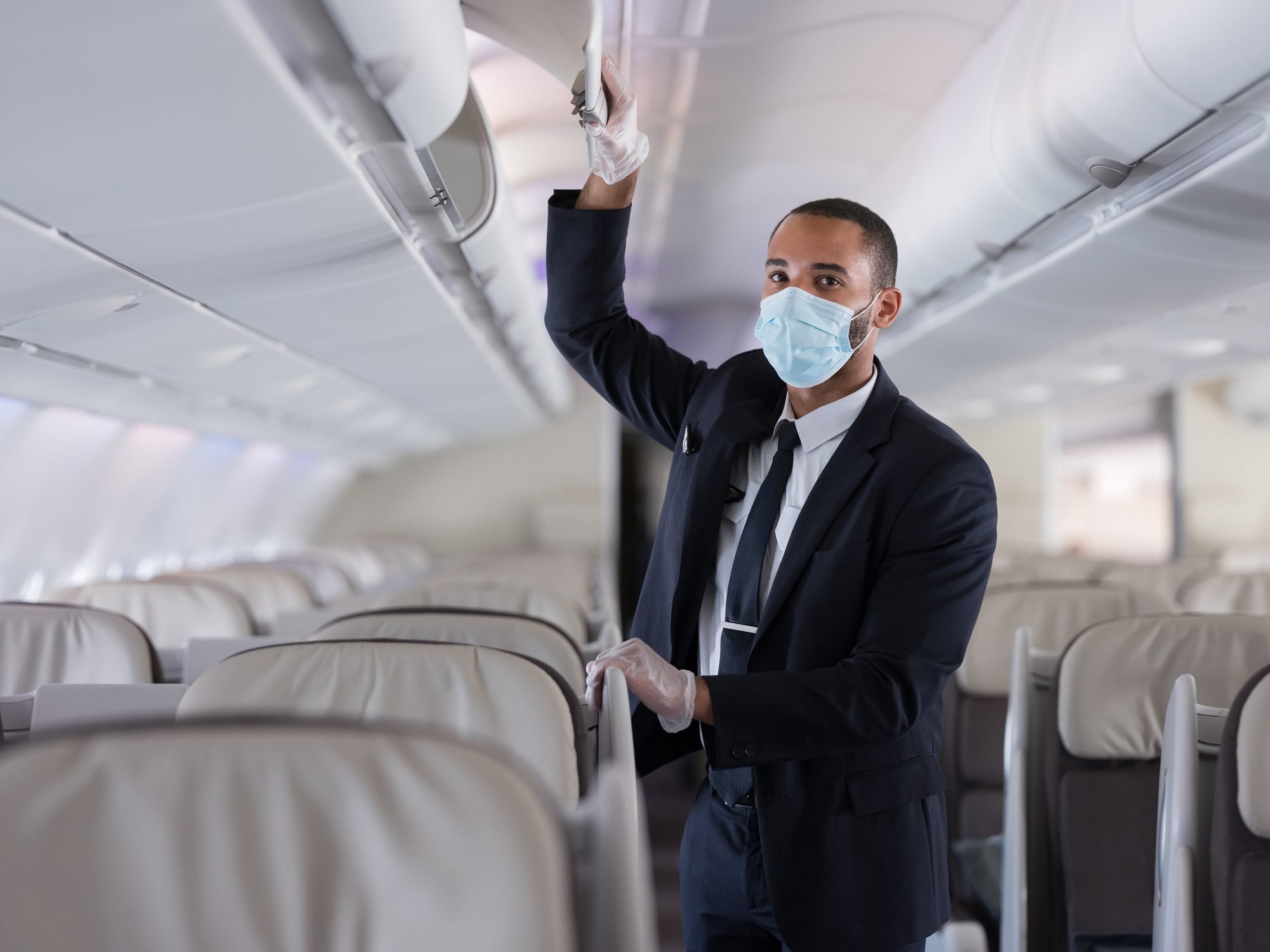 cabin crew on airplane with gloves and mask protection