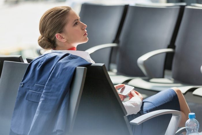 Young attractive businesswoman using smartphone while waiting for her flight in airport