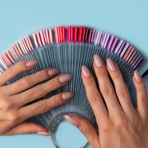 Woman holds in hands collection of color nail polish samples
