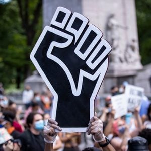 A protestor holds up a large black power fist in the middle of a crowd gathered at Columbus Circle in New York City for a George Floyd Black Lives Matter Protest