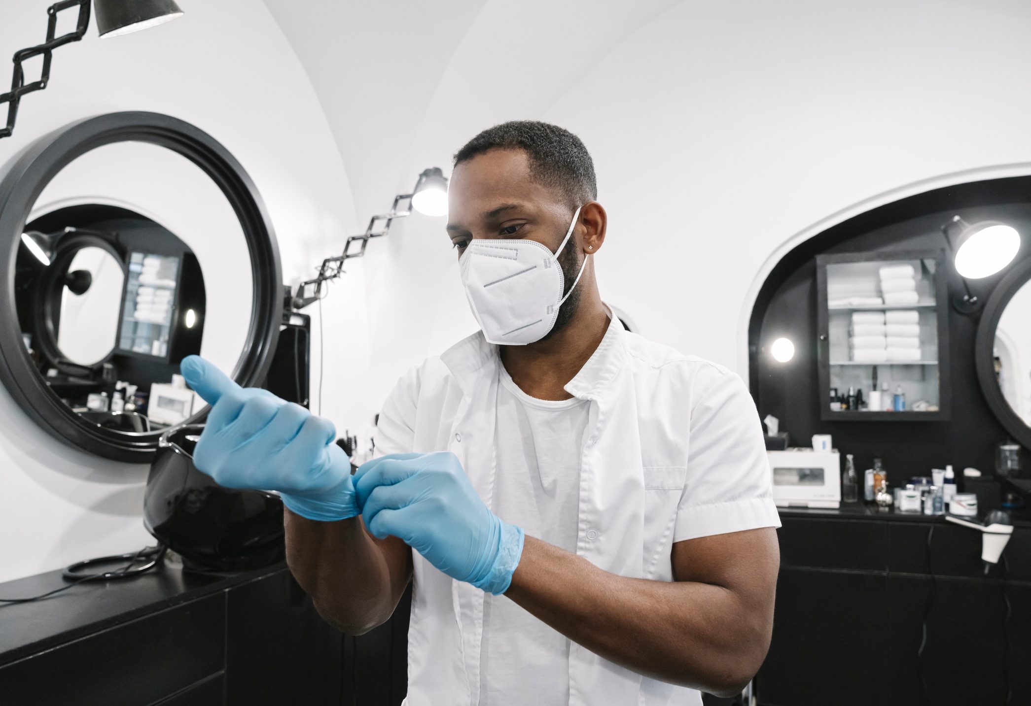 Barber wearing surgical mask putting on reusable gloves