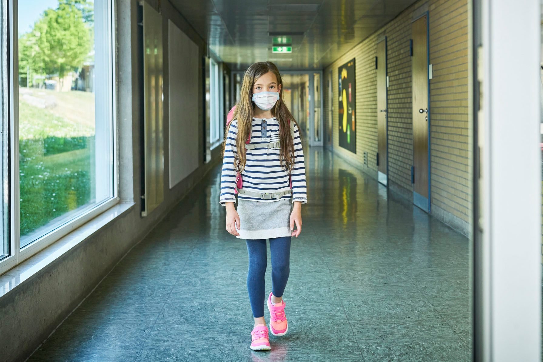 Girl wearing mask walking on school corridor