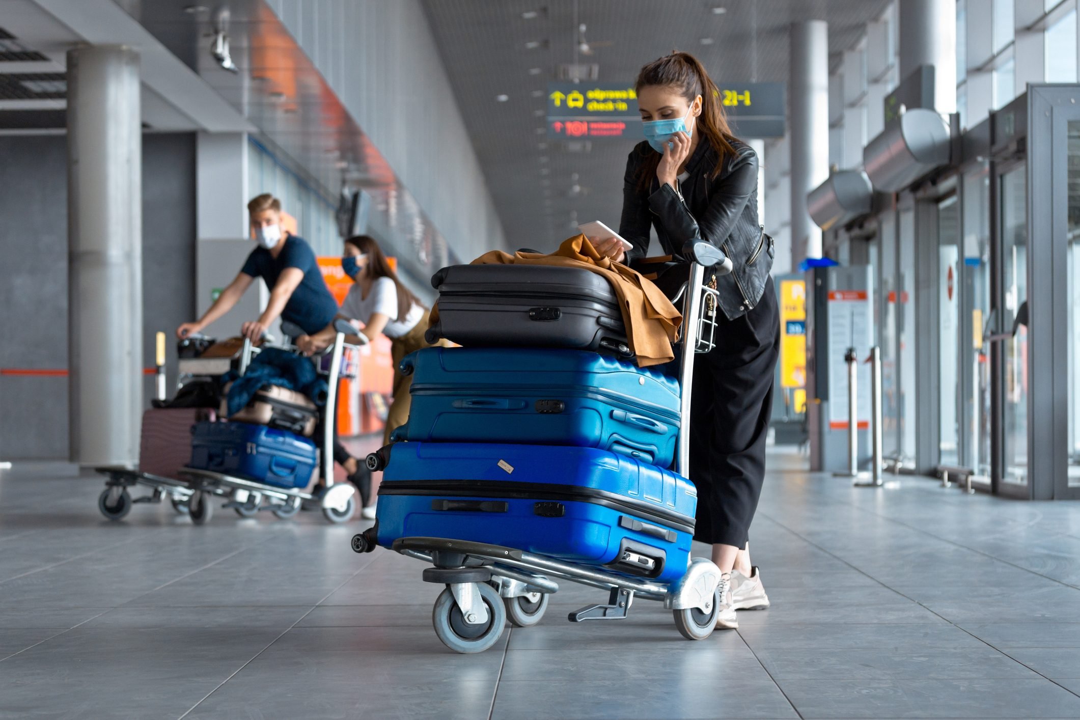 Passengers at the airport with luggage, wearing N95 face masks