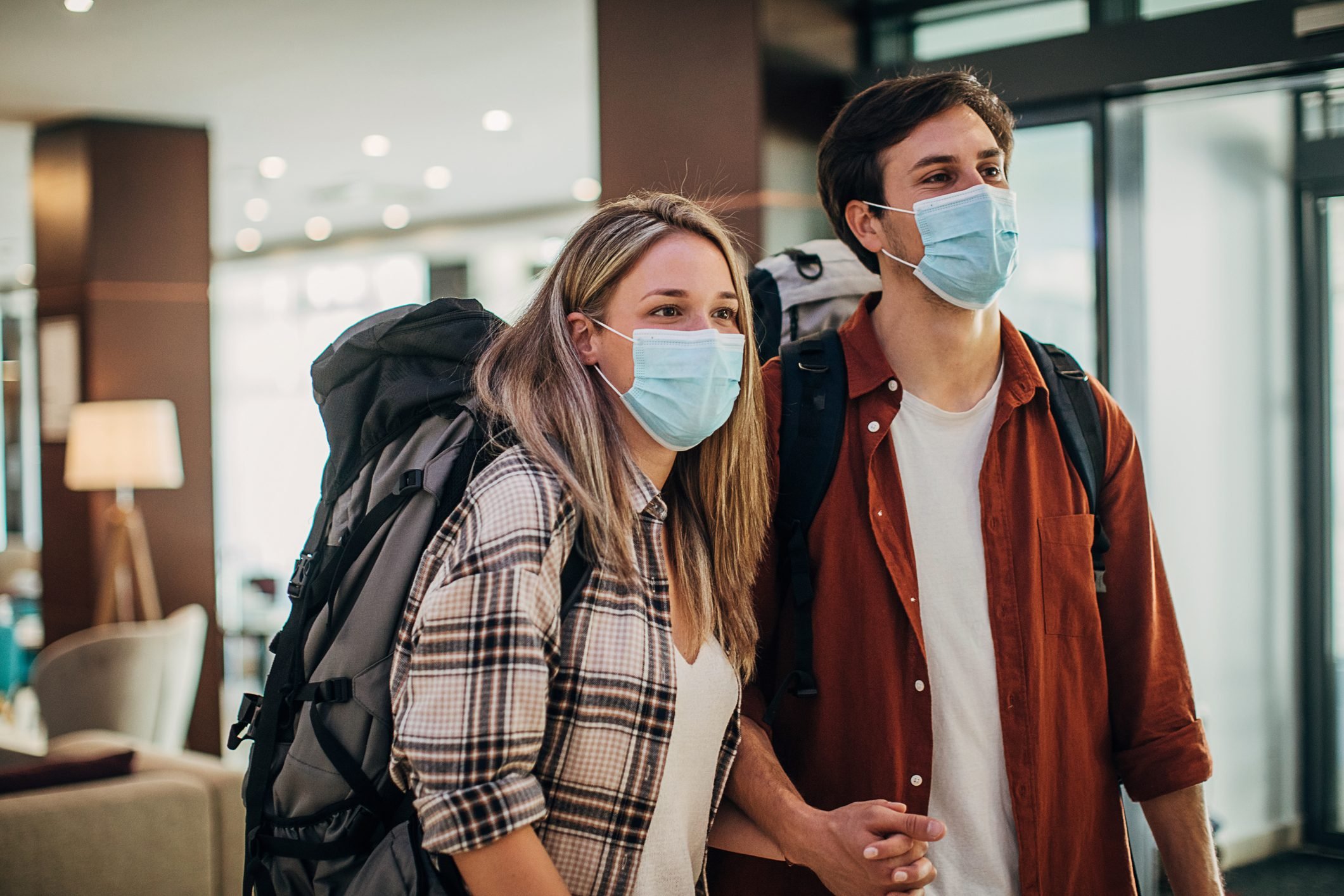 Couple travelers with medical masks just arrived in hotel
