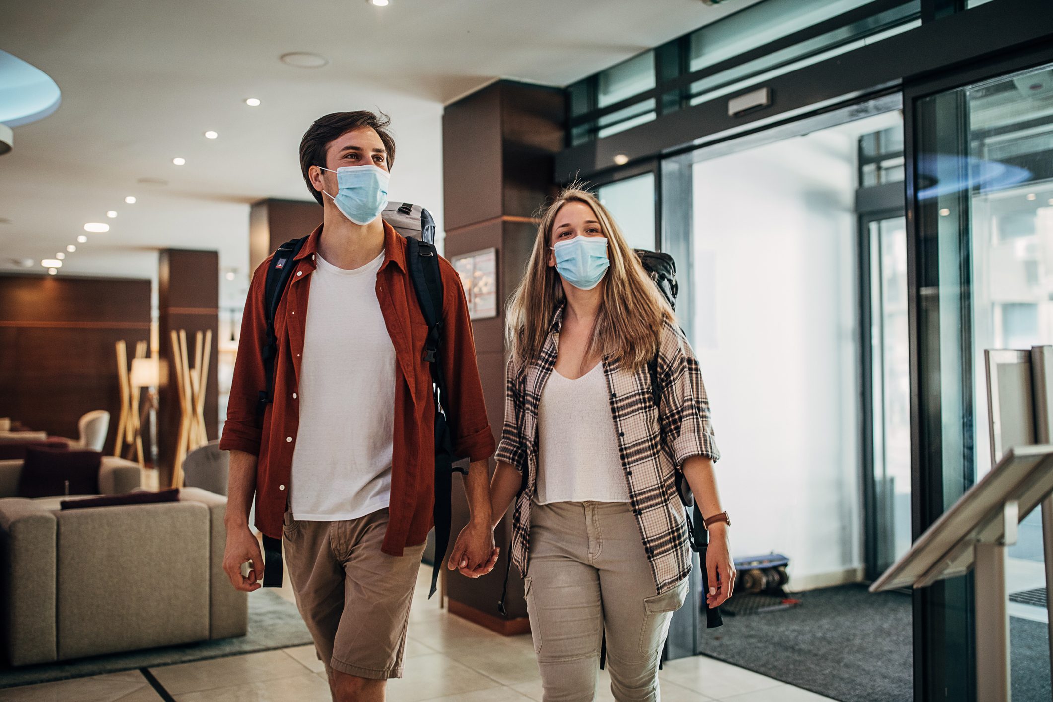 One young couple with protective face masks entering the hotel lobby