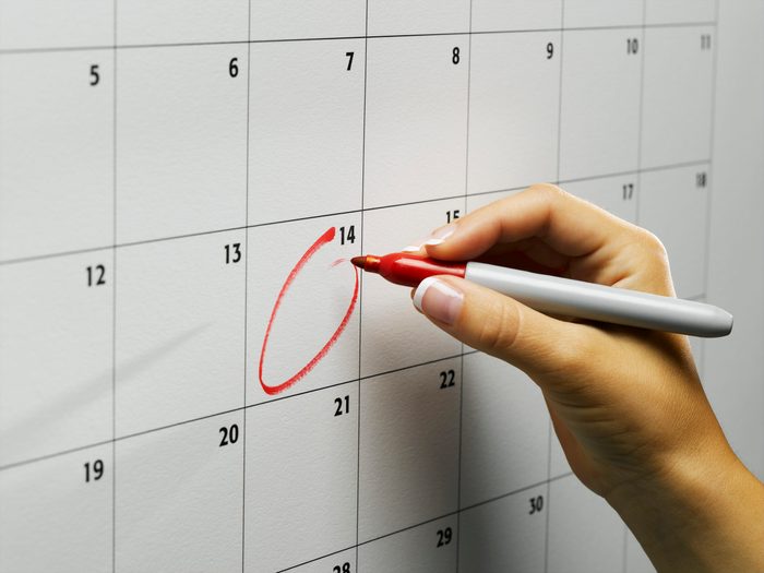 Woman circling day on wall calendar, close-up