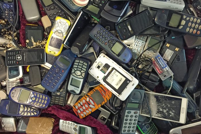 Pile of old, used and partly damaged mobile phones