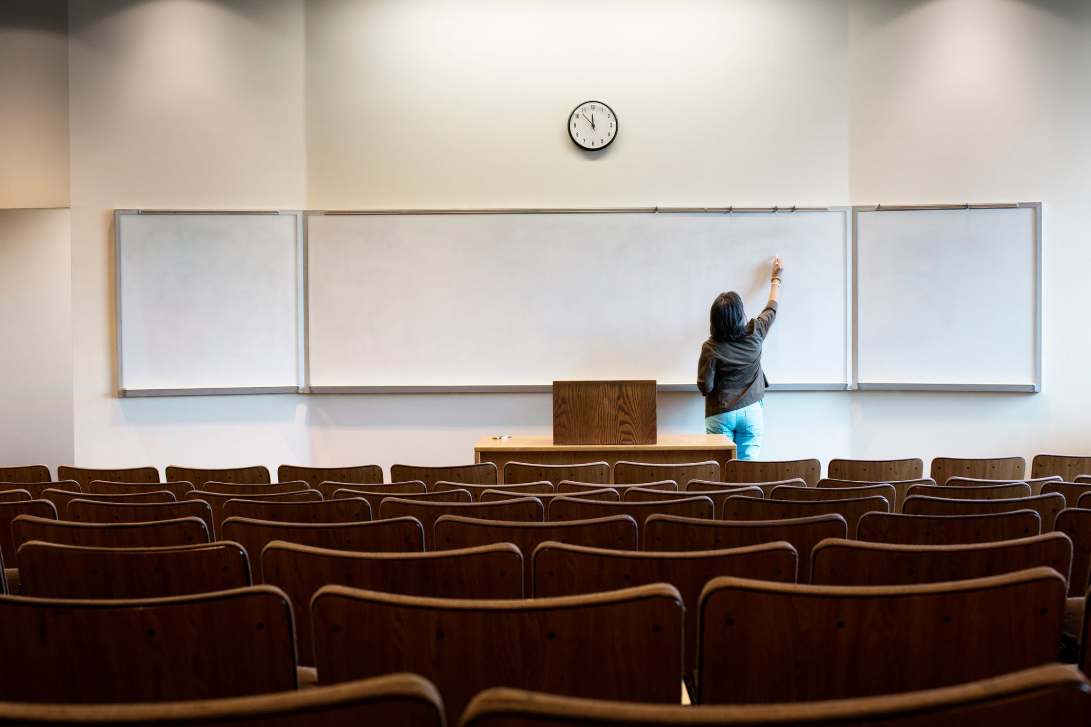 Filipino professor writing on whiteboard in empty lecture hall