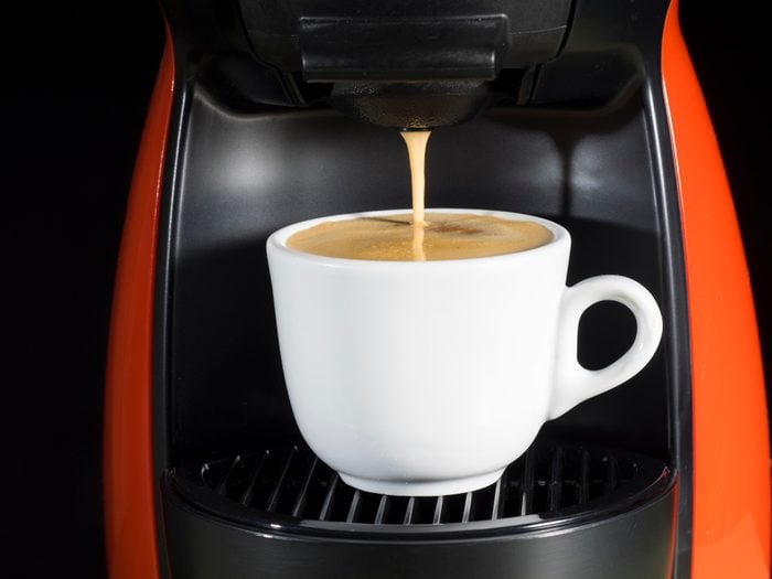 Machine of coffee of capsules with a cup of warm and creamy coffee