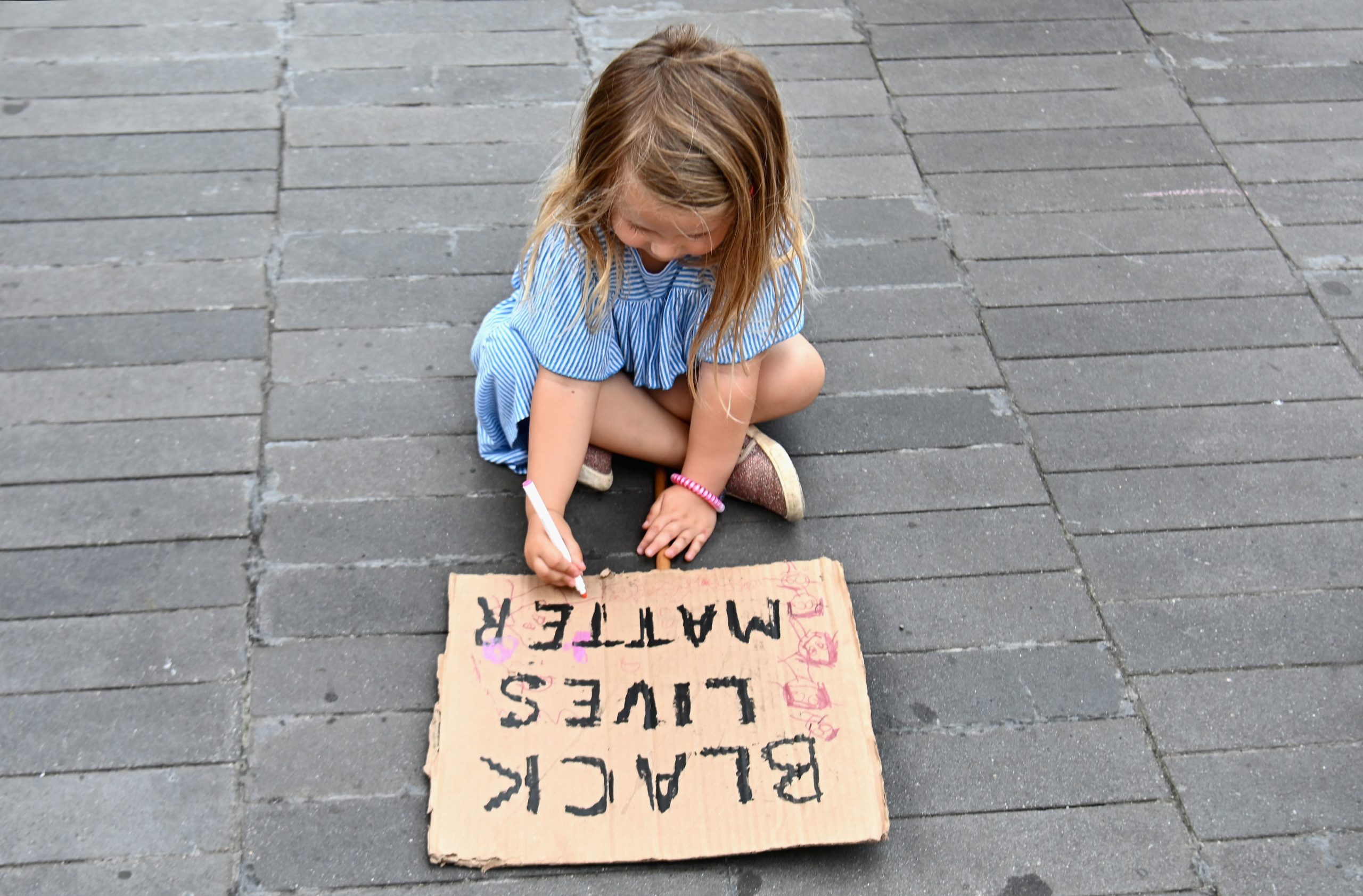 A child paints a sign as families participate in a children's march in solidarity with the Black Lives Matter movement and national protests against police brutality on June 9, 2020 in the Brooklyn Borough of New York City. - George Floyd will be laid to rest Tuesday in his Houston hometown, the culmination of a long farewell to the 46-year-old African American whose death in custody ignited global protests against police brutality and racism.Thousands of well-wishers filed past Floyd's coffin in a public viewing a day earlier, as a court set bail at $1 million for the white officer charged with his murder last month in Minneapolis. (Photo by Angela Weiss / AFP) (Photo by ANGELA WEISS/AFP via Getty Images)
