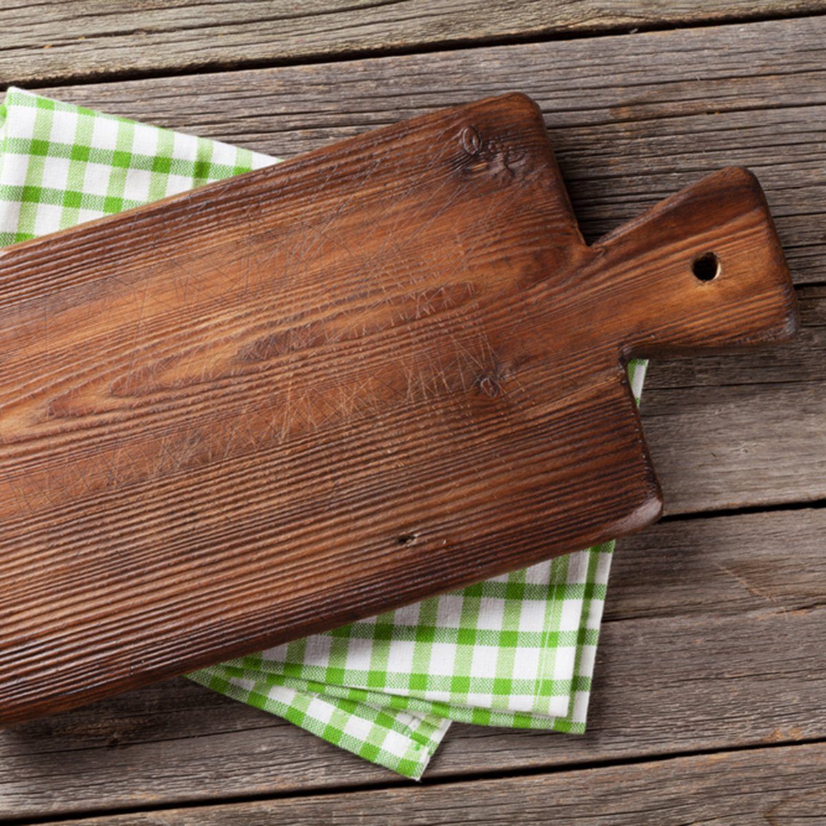 Cutting board over towel on wooden kitchen table.
