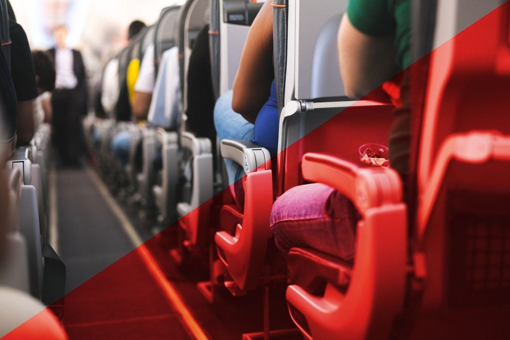 view down the aisle of a crowded plane with red overlay on one half
