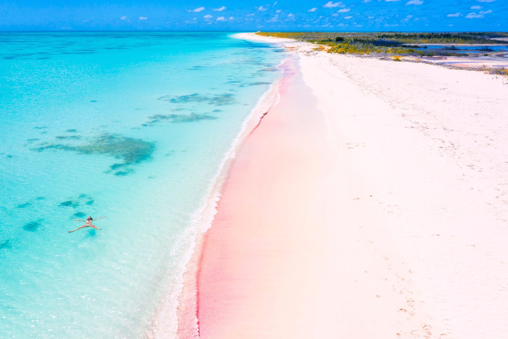 Aerial view of woman floating in turquoise sea, Pink Sand Beach, Barbuda, Caribbean