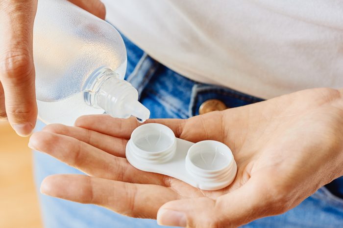 Case for contact lenses and bottle with solution in woman hands
