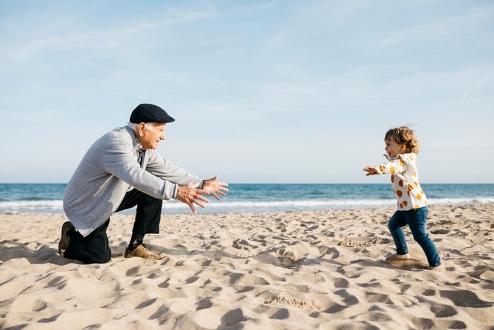 Grandfather playing with his granddaughter on the beach