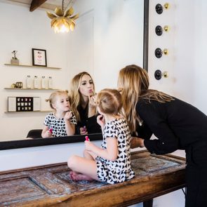 Mother and daughter applying lipstick in mirror