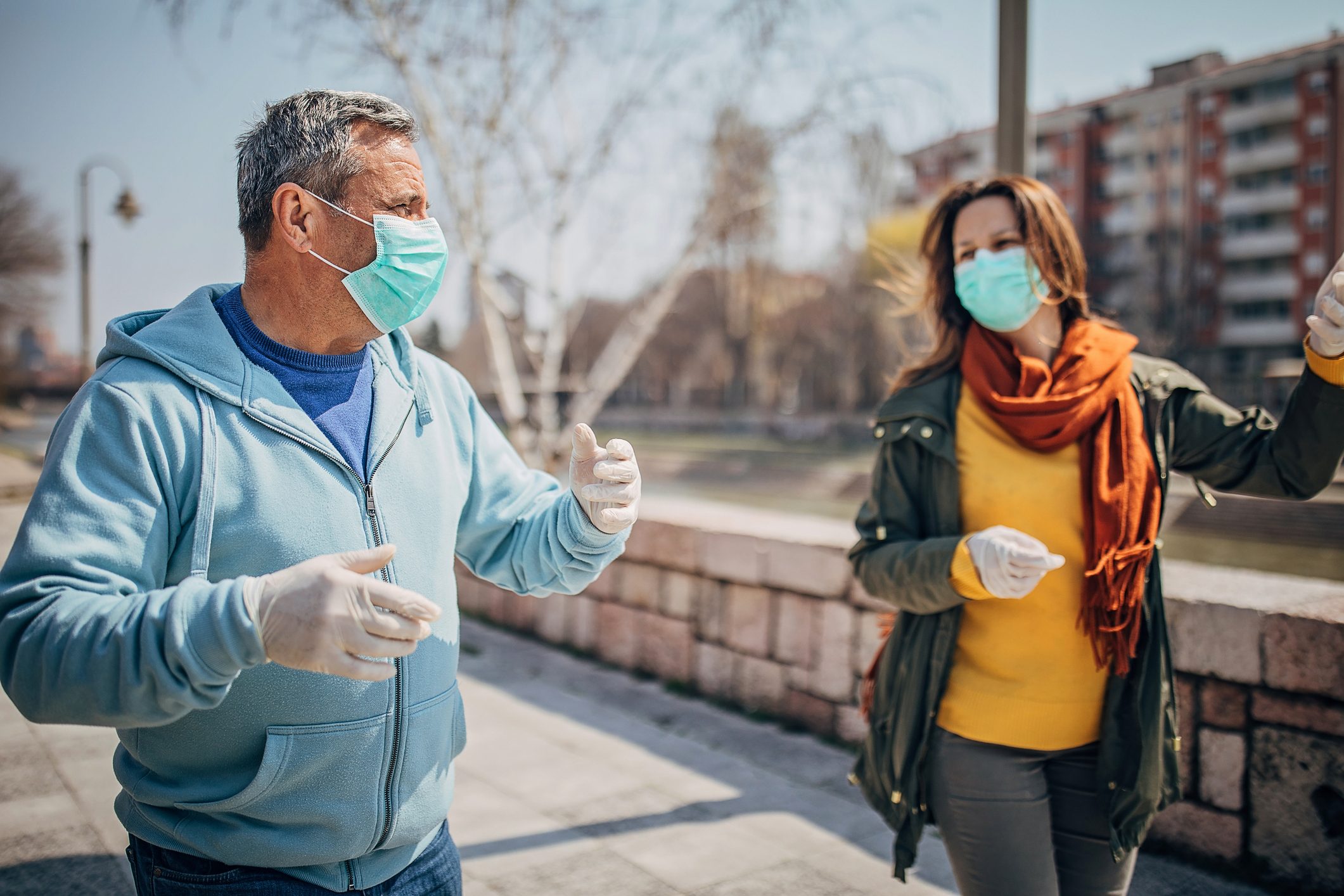Two people with protective mask walking on the street in safe distance