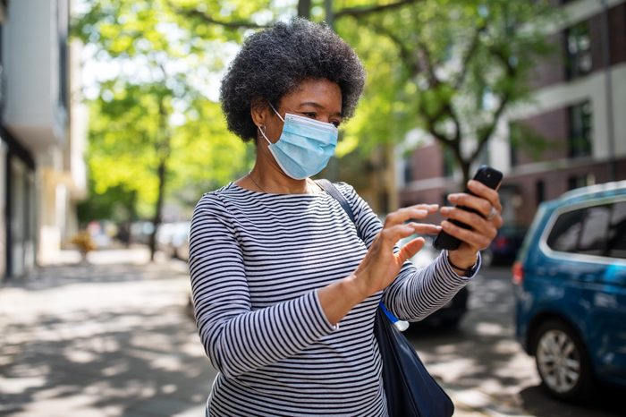 Woman walking on the street during corona virus outbreak using phone