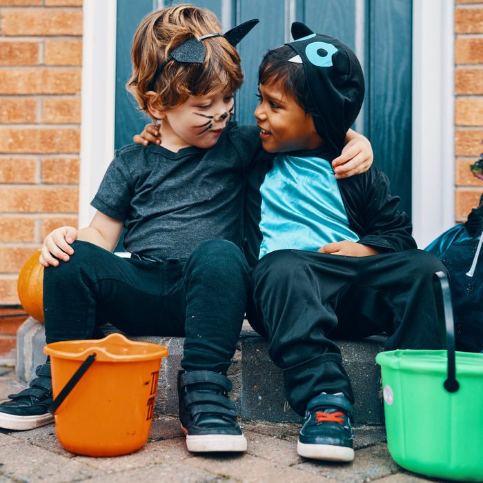 Two children dressed for Halloween with their arms around each others shoulders.