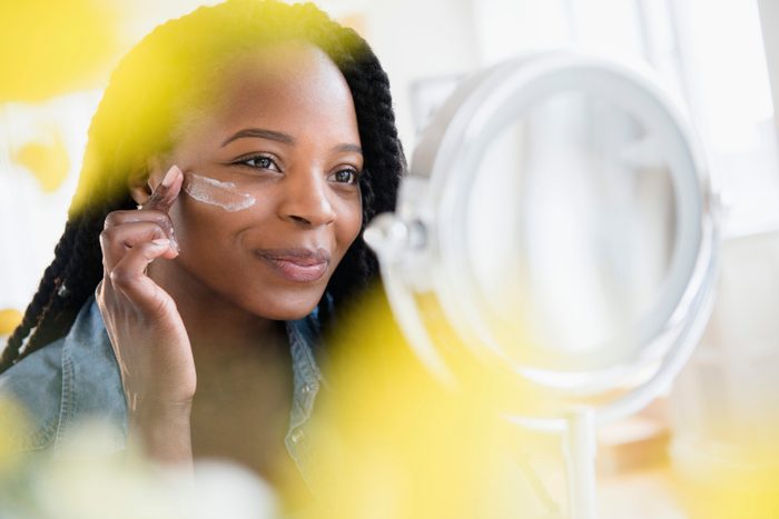 Black woman moisturizing her face