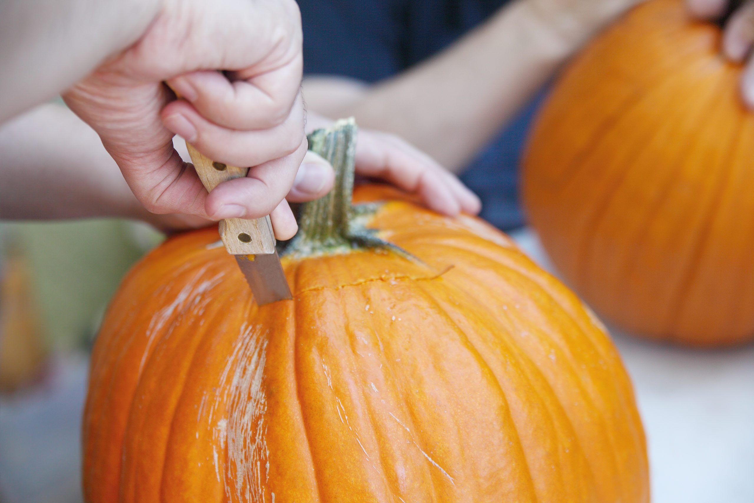 Cropped Hand Of Man Carving Pumpkin For Halloween
