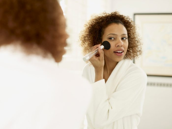 African woman applying makeup