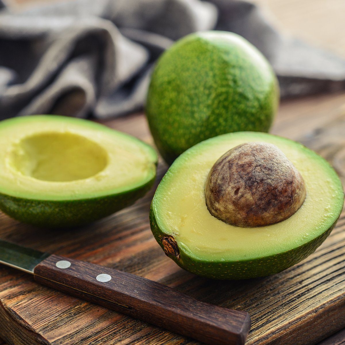 Fresh avocado on cutting board over wooden background