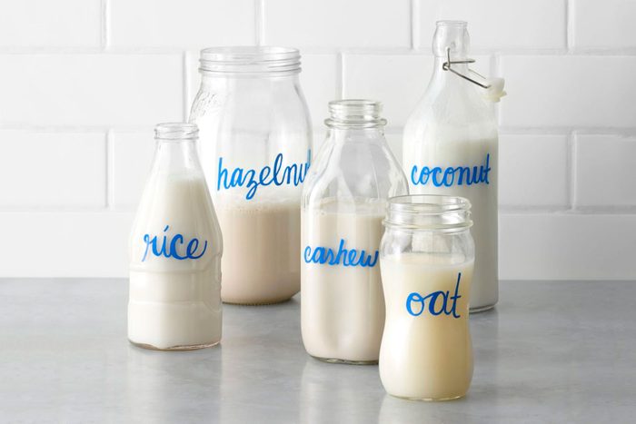 non dairy milk alternatives in various shaped glass jars labeled with hand lettering