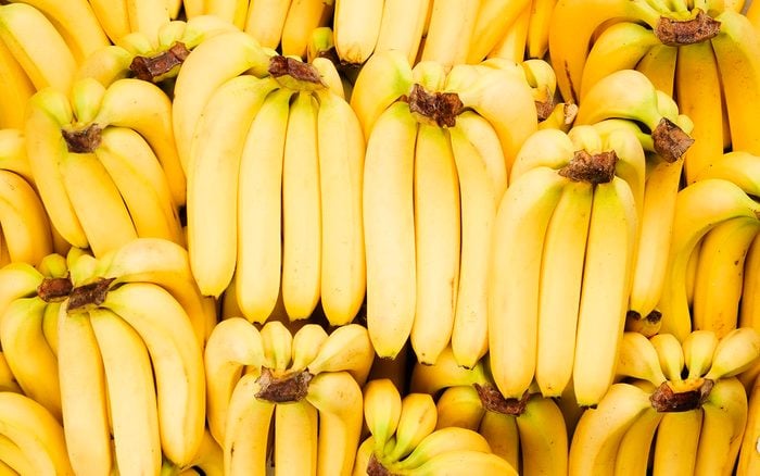 Many bunches of fresh yellow bananas fill the frame