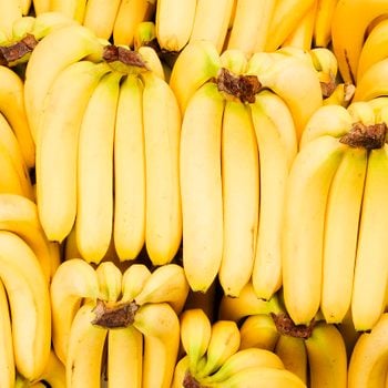 Many bunches of fresh yellow bananas fill the frame