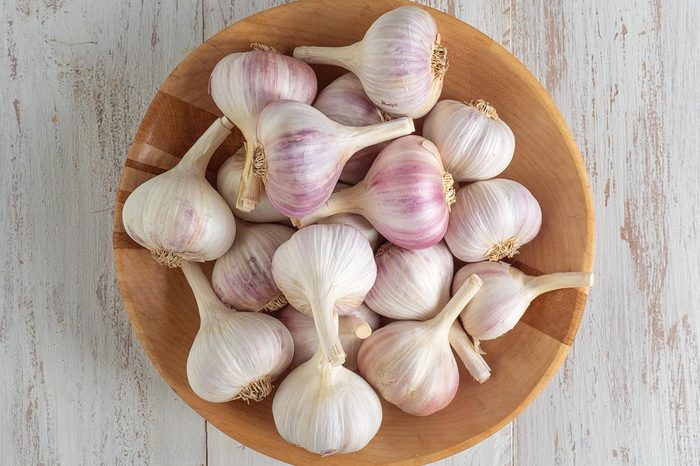 Garlic In A Wooden Bowl On A White Wooden Table