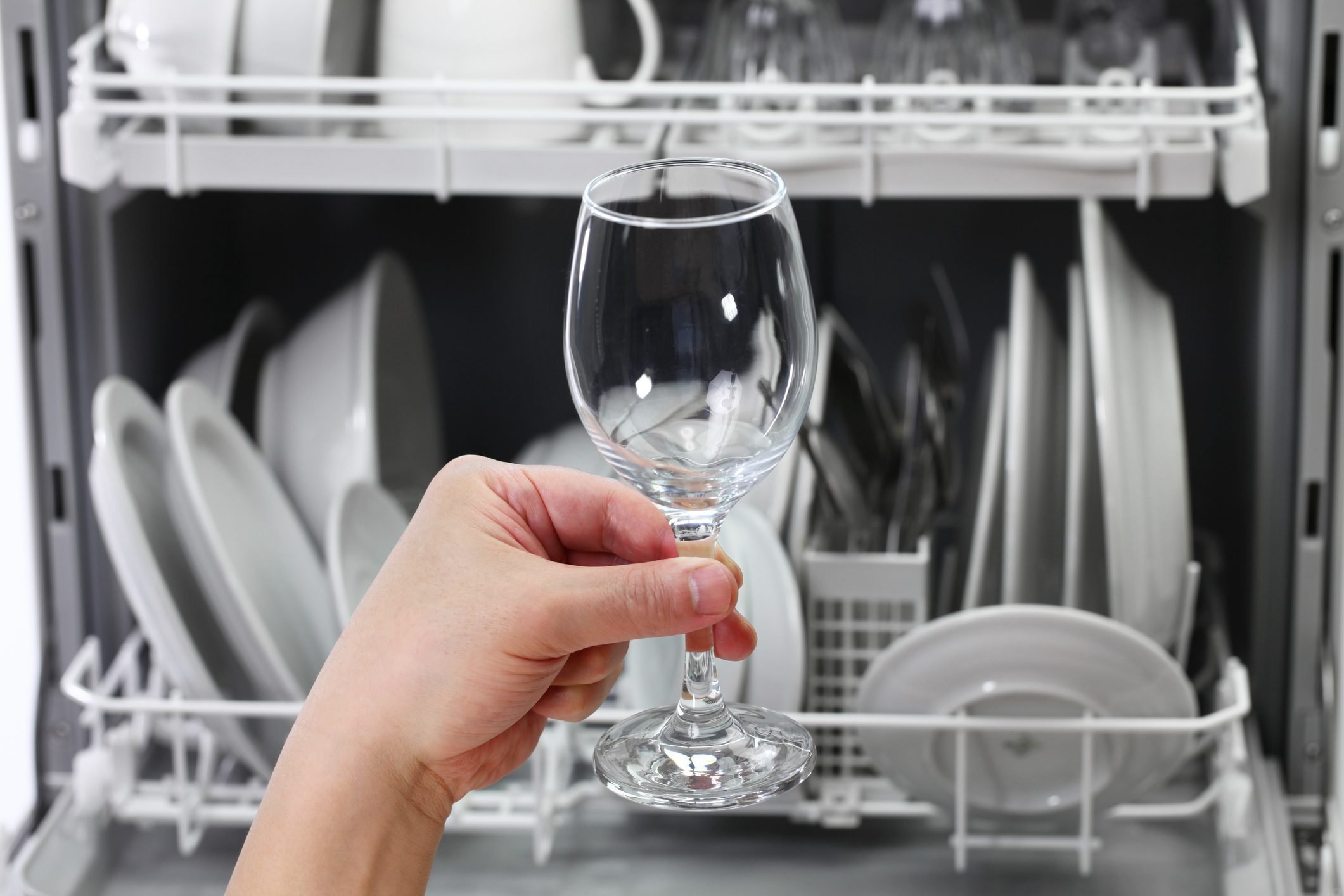 open dishwasher, man hand taking out clean wine glass, after washing