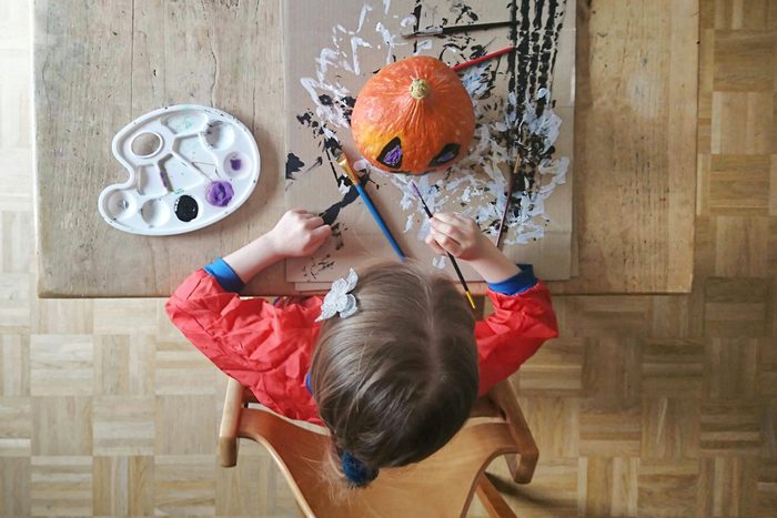Child painting pumpkin with halloween colors