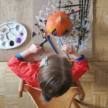 Child painting pumpkin with halloween colors