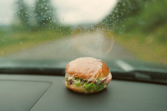 wrapped burger lies on the car dashboard