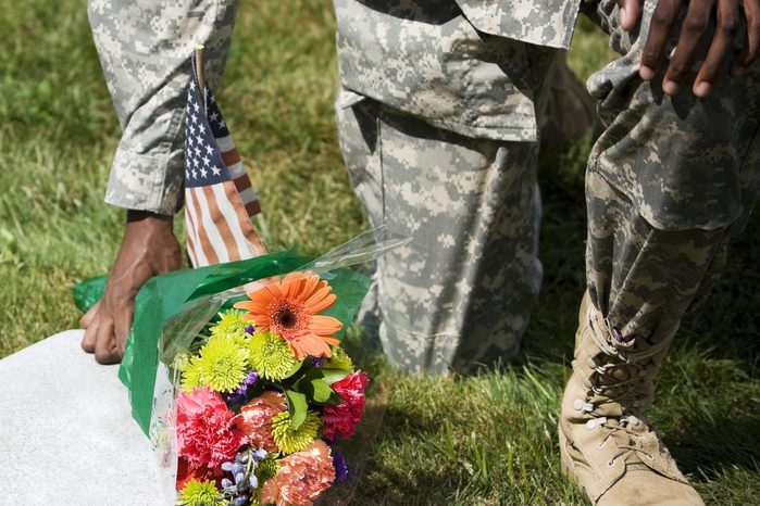 African American Army Soldier Kneeling with Flower Bouquet at Grave