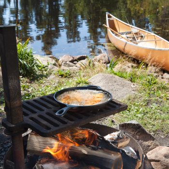 Fish in a frying pan with a canoe in the background