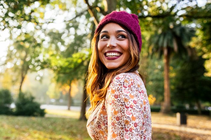 Happy young woman wearing wooly hat in a park in autumn