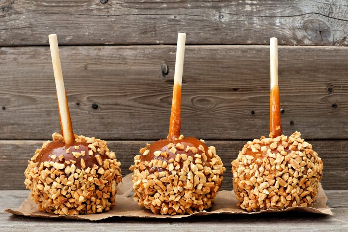 Three caramel apples with nuts against rustic wood