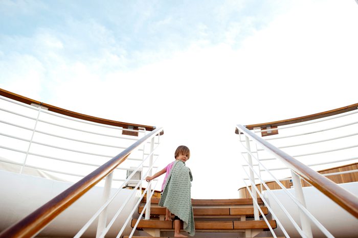 Low angle view of girl climbing steps in cruise ship against sky