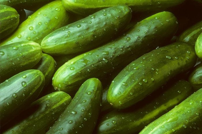 A pile of fresh cucumbers lying diagonally with drops of water