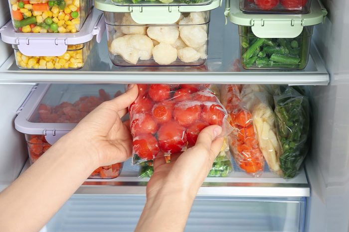 Woman Taking Plastic Bag With Frozen Tomatoes From Refrigerator