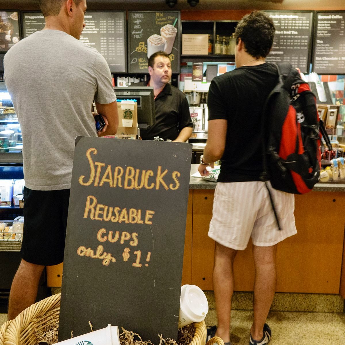 Interior of Starbucks Coffee with customers standing at the counter behind reusable cups sign. (Photo by: Jeffrey Greenberg/Universal Images Group via Getty Images)