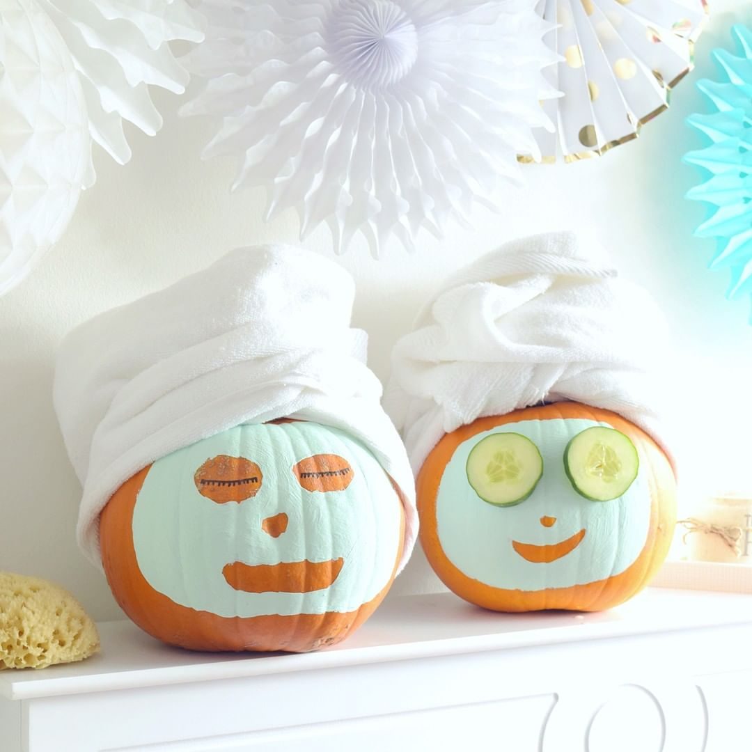pumpkins painted to look like they have spa face masks with towels wrapped around their "heads"