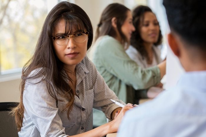Young female creative professional listens to coworker