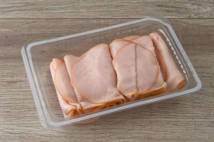 Thin sliced smoked turkey slices in a plastic tray on a table