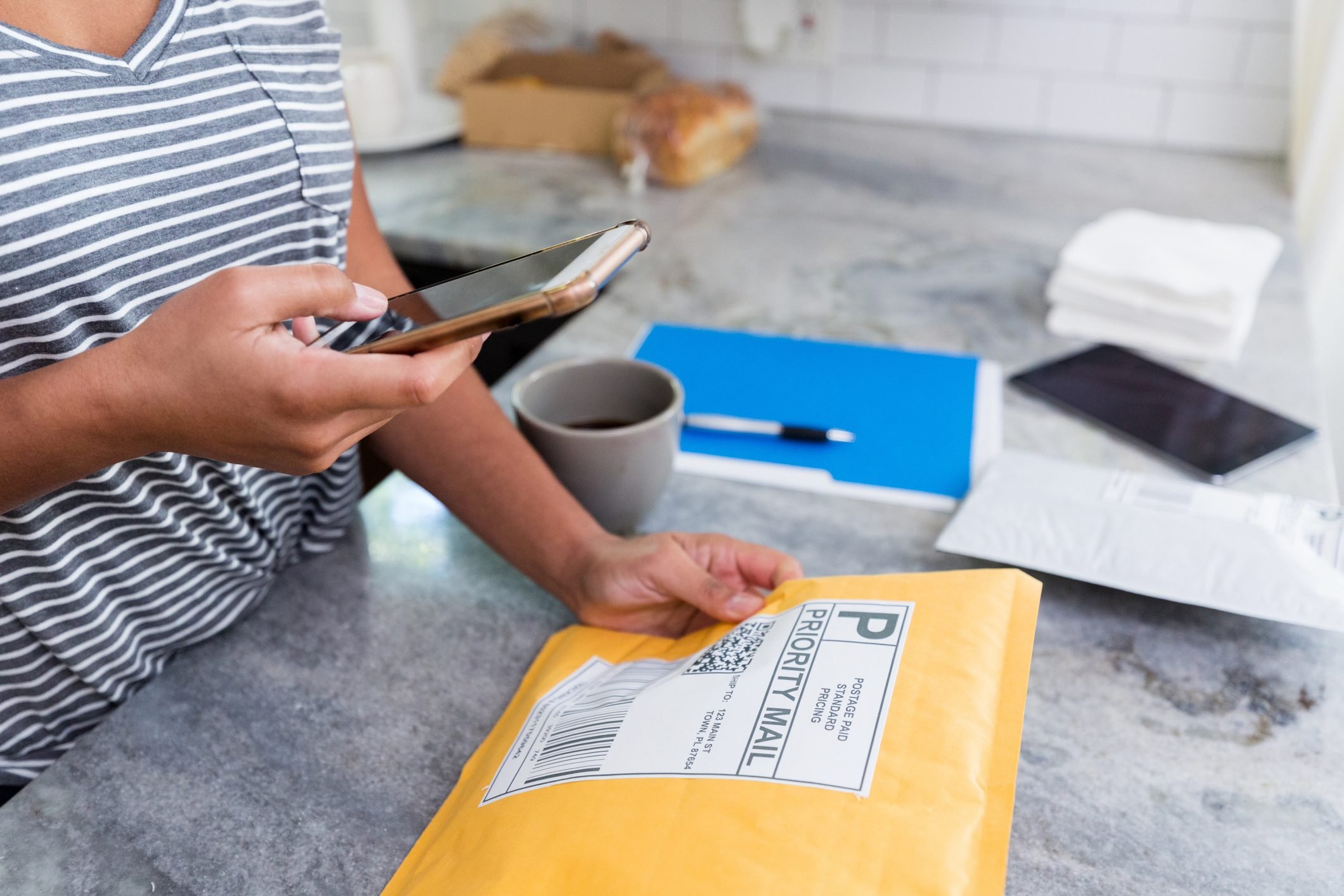 Unrecognizable woman uses mobile app to prep package for mailing